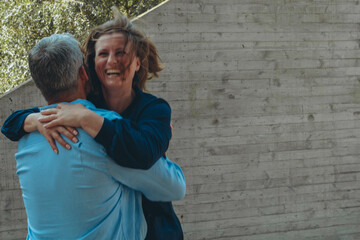 A man and a woman standing hand in hand, looking at the camera.