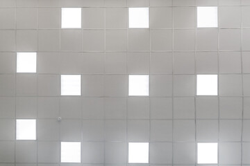 cassette stretched or suspended ceiling with square halogen spots lamps and drywall construction in empty room in house or office. Looking up view