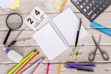 February calendar with number  24. Copy of space note. Top view of blank notepad. Space for text in a checkered sheet, stationery background with accessories.