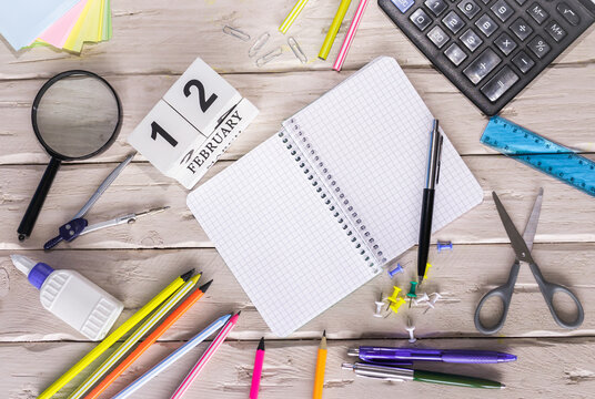 February calendar with number  12. Copy of space note. Top view of blank notepad. Space for text in a checkered sheet, stationery background with accessories.