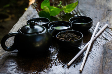 A small black teapot with a Japanese tone with the glass is arranged on an antique wooden table