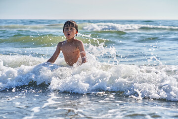 An 11 year old boy in having fun in the sea waves.