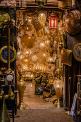 A dimly lit shop in Marrakesh’s medina glows warmly, filled with an array of intricately designed brass lanterns and lamps that create a cozy, golden ambiance inside