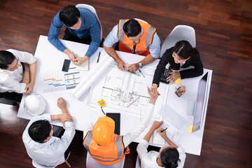 Top view banner of diverse group of civil engineer and client working together on architectural project, reviewing construction plan and building blueprint at meeting table. Prudent