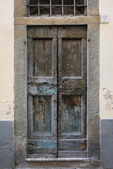 Shabby old double door entrance of stone building in Europe. Vintage wooden doorway of ancient stone house. Simple grey brown wood door. Architecture in Italy.