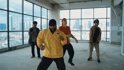 Multicultural hipster group looking at camera while perform break dancing at building with sky scrapper or city view. Street dancer team looking at dancer performance. Outdoor sport 2024. Hiphop.