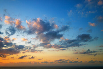 Fototapeta premium Majestic dusk in Atlantic Ocean. Sunset sky twilight in the evening with colorful sunlight. Abstract nature background. Dramatic orange and blue sky with dark and yellow clouds.