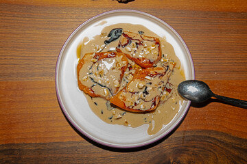 A plate of pumpkin dessert with tahini, molasses and hazelnut pieces on the table.