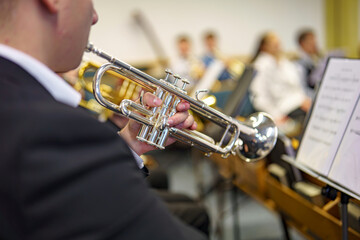 A musician in an orchestra plays a musical composition on a trumpet in an orchestra.