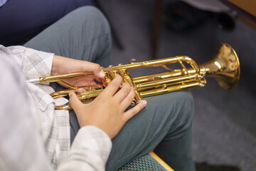 A musician in an orchestra plays a musical composition on a trumpet in an orchestra.