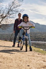 A happy mother teaching her son to ride a bike