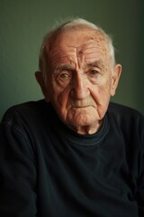 Obraz premium Thoughtful Elderly Man Portrait on Olive Green Background for Reflection Themes