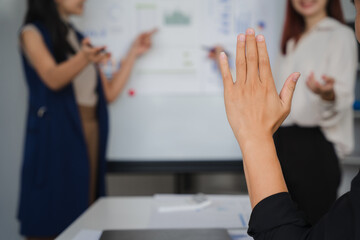  A Hand Raised: A woman's hand reaches towards the board, capturing a moment of proactive engagement and active participation in a modern business meeting. This image evokes a sense of curiosity.