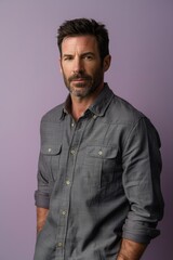 Obraz premium Confident Middle-Aged Man in Grey Shirt Against Soft Lavender Background for Professional Use