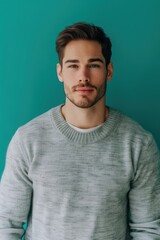 Fototapeta premium Thoughtful Mid-30s Man in Grey Sweater Against Vibrant Teal Background for Design Use