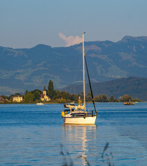 Anchored sail boat on the waters of the Upper Zurich Lake (Obersee) near the picturesque village of Busskich, St. Gallen, Switzerland