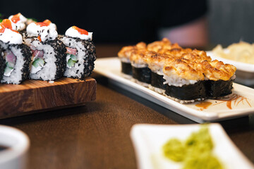 Composition of different kinds of sushi rolls placed on wooden board. Fresh Set of delicious Japanese Shushi. Eating sushi with chopsticks close up, food takeout. Variety of types sushi with caviar