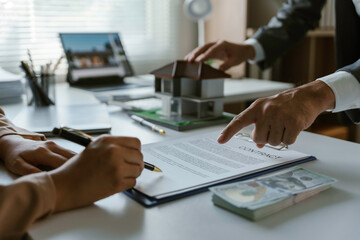Client is signing a contract to purchase a new home with their real estate agent pointing at the signature line
