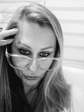 mulher loira, com &oacute;culos, fotografada em preto e branco, com express&atilde;o de frustra&ccedil;&atilde;o
