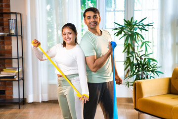 Indian Asian couple or friends performing resistance band exercises in a high-end fitness studio