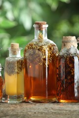 Different tinctures in bottles on wooden table outdoors, closeup