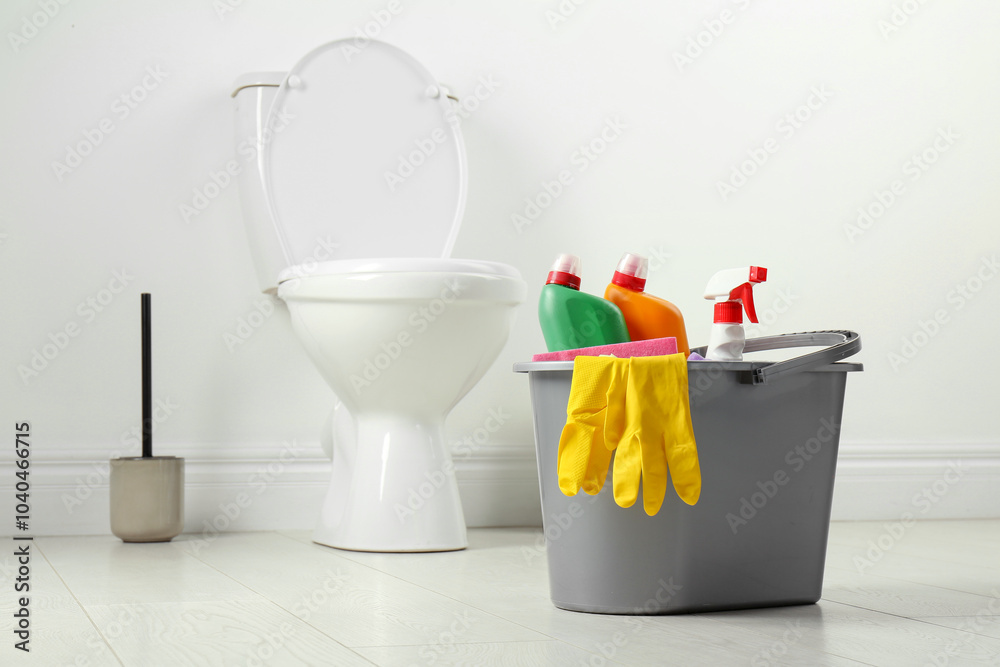 Wall mural Bucket with different toilet cleaners and gloves on floor in bathroom