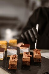 Chef Decorating Pastry with Tweezers on a Plate with Assorted Pastries