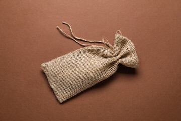 One burlap sack on brown background, top view