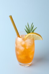 Tasty refreshing drink with straw in glass on light blue background