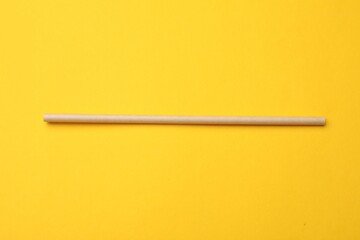 Bamboo drinking straw on yellow background, top view