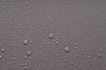 Water drops on gray background, top view