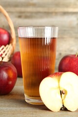 Glass of juice and apples on wooden table