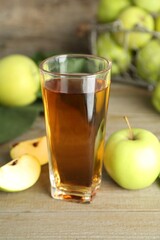 Glass of juice and apples on wooden table