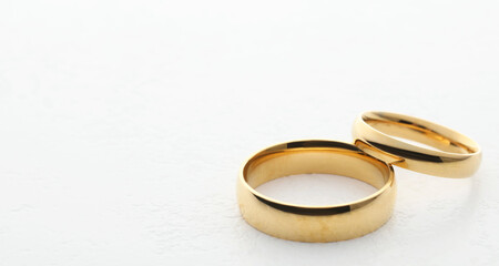 Beautiful golden wedding ring on white table, closeup. Space for text