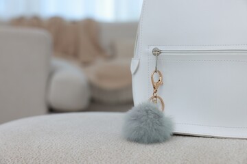 Stylish backpack with faux fur keychain on soft surface indoors, closeup. Space for text