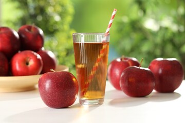 Tasty apple juice in glass and fresh fruits on white table outdoors