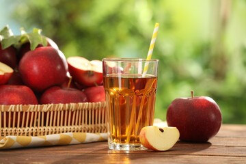 Tasty apple juice in glass and fresh fruits on wooden table outdoors