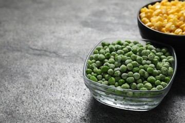 Frozen green peas and corn kernels on grey table, closeup. Space for text