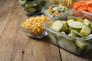 Different frozen vegetables on wooden table, closeup