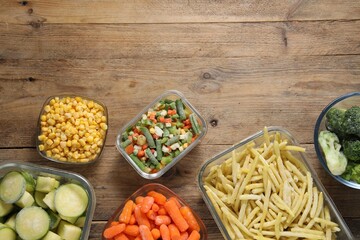 Different frozen vegetables on wooden table, flat lay