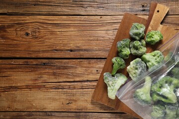 Frozen broccoli out of plastic bag on wooden table, top view. Space for text