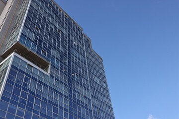 Obraz premium Exterior of modern building with many windows against blue sky, low angle view