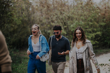 Fototapeta premium A cheerful group of friends enjoying a walk in nature, surrounded by lush greenery. They are smiling and laughing, showing a sense of joy and camaraderie during their outdoor adventure.