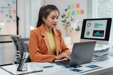 Businesswoman working with laptop analyzing financial charts and graphs sitting at her desk in the office