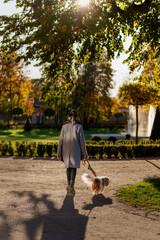 Woman Walking Dog in Sunlit Autumn Park