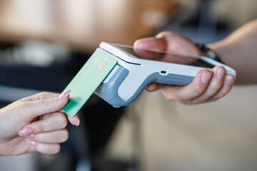 Customer paying with credit card using POS machine indoors, closeup