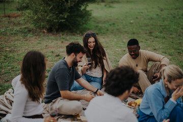 A group of multiracial friends enjoying a relaxing picnic on a cloudy day outdoors. Laughter and camaraderie fill the air as they share food and stories.