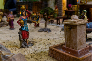 Backgrund composed of ceramic figurines from Nativity scene. A shepherdess goes to the fountain to fill water jugs. High quality photo