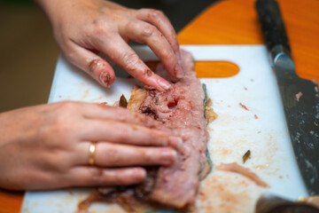 Delicate hands skillfully navigate through fish, meticulously removing bones to prepare a fresh fillet, highlighting the artistry and care in culinary preparation