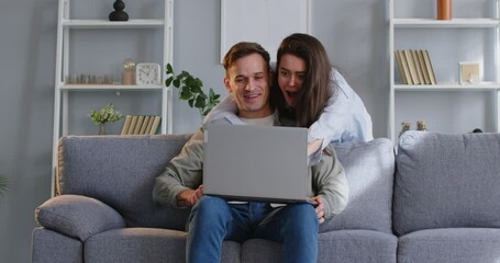 Excited couple at home, man showing laptop screen and feel euphoric to win money online, happy wife, woman overjoyed to get good mail, special offer, news at computer, invitation, internet sale, prize
